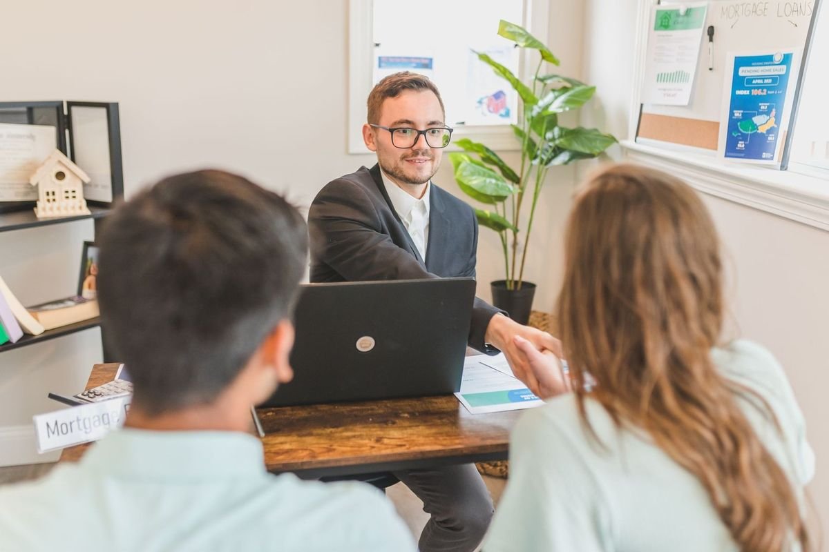 Professionnels discutant autour d'un ordinateur dans un bureau décoré