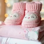 Chaussons tricotés roses posés sur couches bébé aux motifs animaux