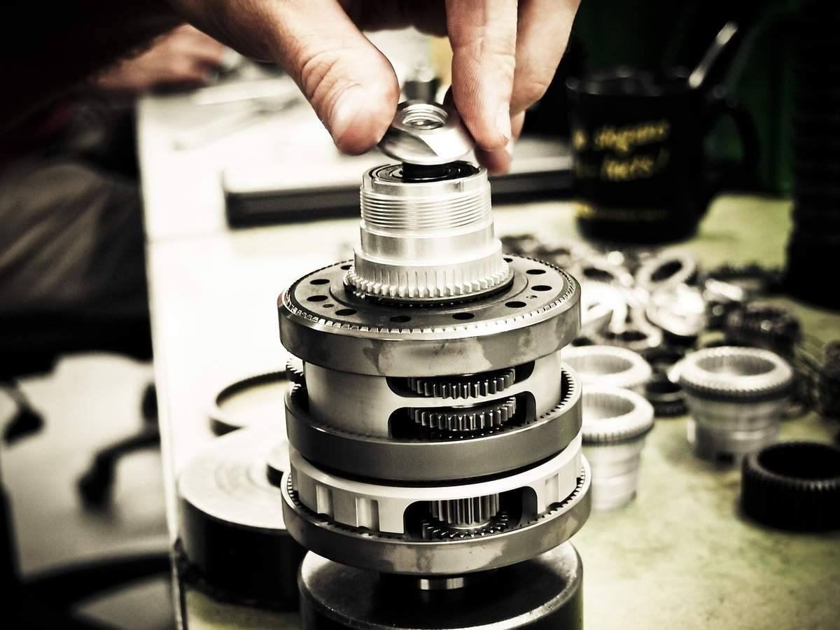 Une main place un petit composant sur un assemblage de pièces mécaniques