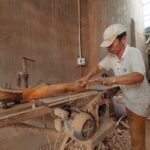 Homme en atelier, scie à table, planche de bois, sciage en cours