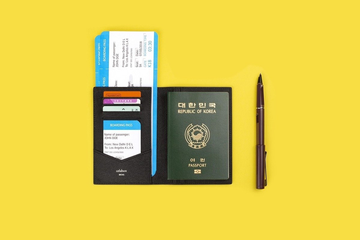 Passeport noir ouvert, documents et carte à l'intérieur, stylo à côté sur fond jaune Passeport noir ouvert, documents et carte à l'intérieur, stylo à côté sur fond jaune