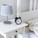 Table de nuit avec lampe et réveil, lit avec oreiller