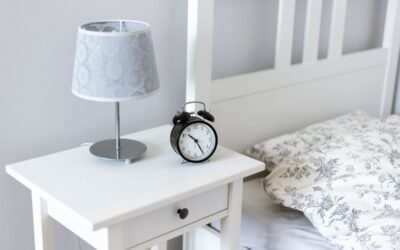 Table de nuit avec lampe et réveil, lit avec oreiller