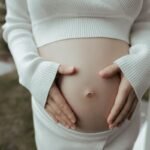 Une femme enceinte caresse doucement son ventre nu